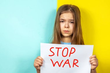Bir kız ağlıyor, elinde Ukrayna bayrağının arka planına karşı bir DUR Savaş posterini tutuyor. Ukrayna 'daki savaşı durdurun. Ukrayna 'da barış kavramı. Yazı metni için yer