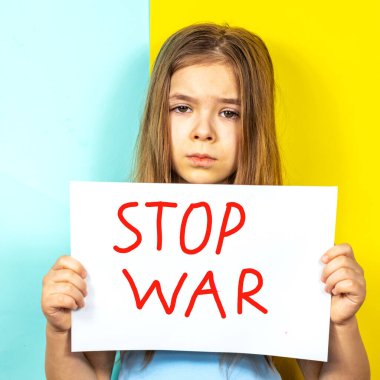 Üzgün bir kız elinde Ukrayna bayrağının arka planına karşı bir STOP Savaş posterini tutuyor. Ukrayna 'daki savaşı durdurun. Ukrayna 'da barış kavramı.