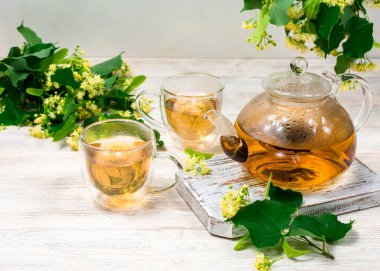 Çaydanlık ve iki fincan çay, ahşap bir masada ıhlamur ağacı..