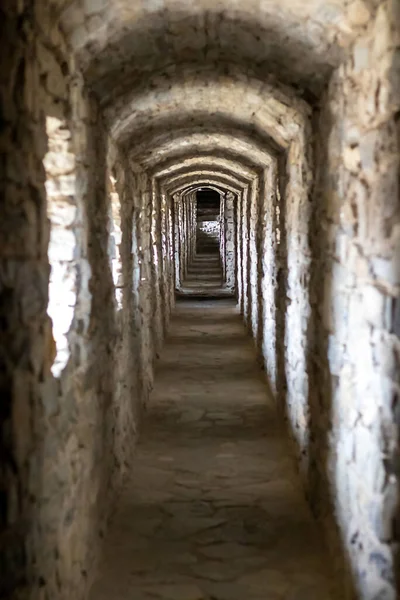 A long stone tunnel corridor with windows in an old castle. Selective focus