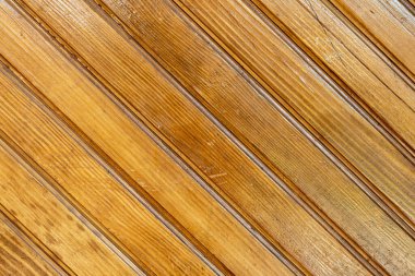 Brown background texture of a wooden fence made of diagonal planks of natural wood. Wooden background from wooden planks