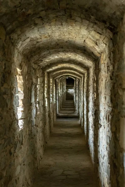 A long stone tunnel corridor with windows in an old castle. Selective focus