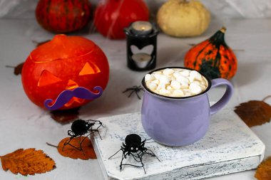 Cadılar Bayramı balkabağı ve kahve fincanı üzerinde kurabiyeler olan gri bir duvarın arkasında hayaletler, yarasalar, örümcekler, mumlar, balkabakları. Yaprak. Seçici odak