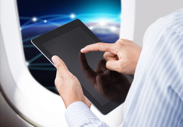 Podnikatel drží digitálním tabletu v letadle s pozadím horizont — Stock fotografie