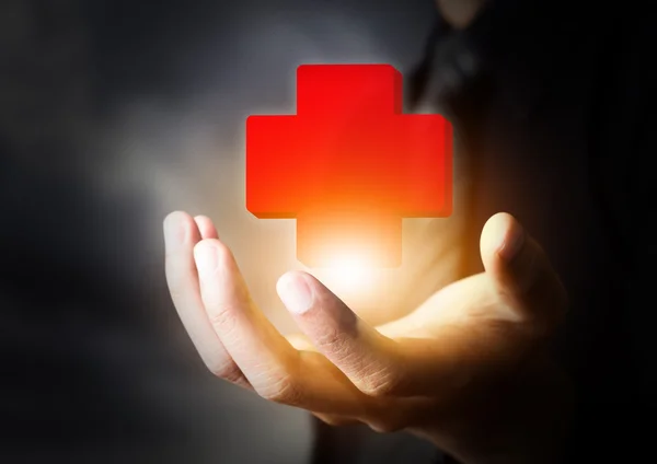 Mano sosteniendo icono de primeros auxilios, concepto de seguro — Foto de Stock