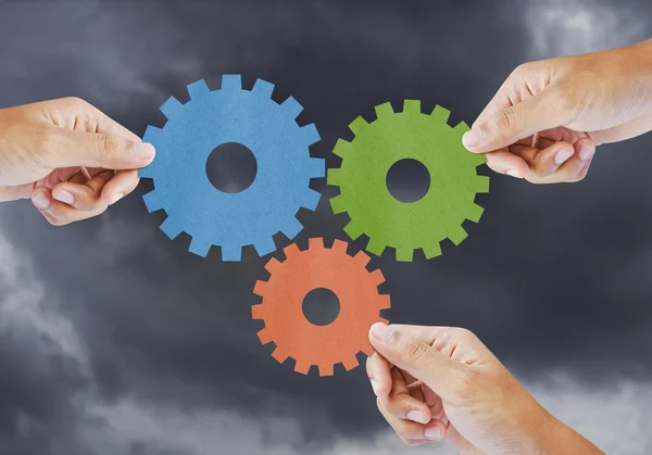 Hand show gear to teamwork as concept in storm clouds — Stock Photo, Image