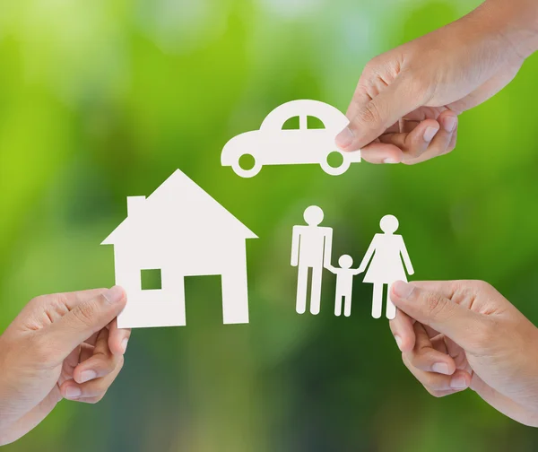 Mano sosteniendo una casa de papel, coche, familia sobre fondo verde — Foto de Stock