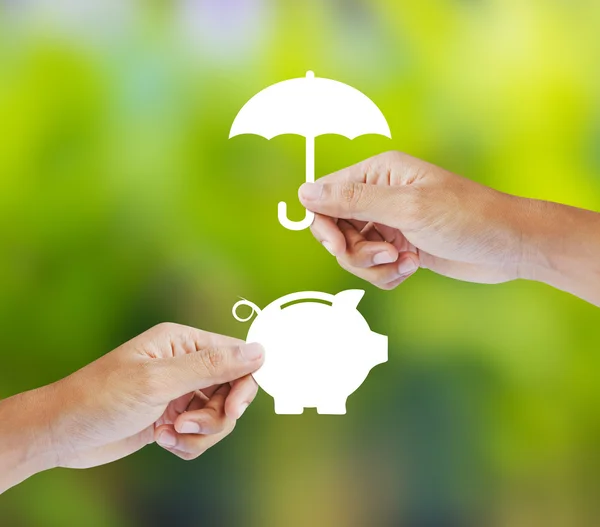 Mão segurando um banco de papel piggy e guarda-chuva — Fotografia de Stock