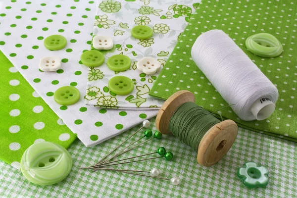 Accessori per il cucito: fili, tessuto, bottoni in bianco-verde Immagini Stock Royalty Free