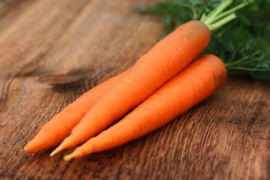 eski bir ahşap zemin üzerinde üç turuncu havuç