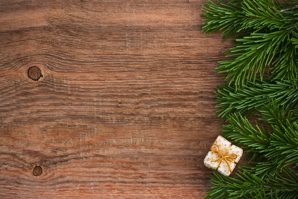 Christmas card. Fir-tree branches with a gift box with a Golden — Stock Photo, Image