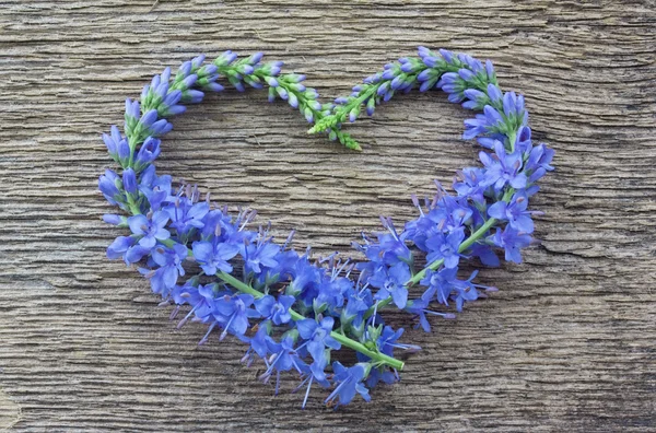 Wild blue flowers in the form of heart on a wooden background — Stock Photo, Image