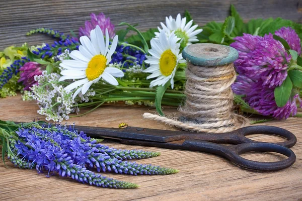 Wilde bloemen, schaar en hank van draden op een oude houten rug — Stockfoto