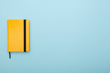 Mavi arka planda siyah yer imi olan sarı not defteri var. Çalışma ve öğrenim aracı