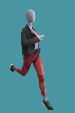 Yeşil arka planda izole edilmiş spor giyimli, çalışan bir kadın vitrin mankeninin tam boy görüntüsü