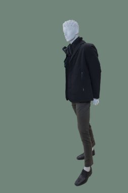 Yeşil arka planda izole edilmiş, kalın ve modaya uygun kıyafetler giyen bir erkek mankenin tam boy görüntüsü.