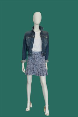 Mavi arka planda izole edilmiş şık kıyafetler giyen bir kadın vitrin mankeni.