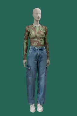 Yeşil arka planda izole edilmiş şık kıyafetler giyen bir kadın vitrin mankeni.