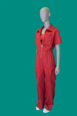 Full length image of a female display mannequin wearing fashionable red overalls isolated on a blue background
