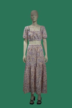 Yeşil arka planda üst ve etek giyen bir kadın vitrin mankeninin tam boy görüntüsü