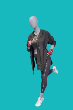 Yeşil arka planda izole edilmiş spor giyimli, çalışan bir kadın vitrin mankeninin tam boy görüntüsü