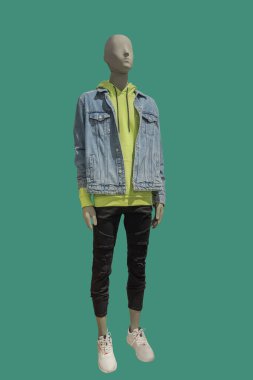 Full length image of a male display mannequin wearing fashionable clothes isolated on green background
