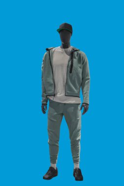 Mavi arka planda izole edilmiş spor giyimli bir erkek vitrin mankeni.