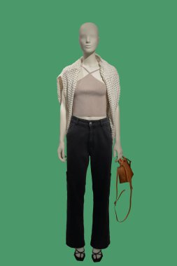 Yeşil arka planda izole edilmiş şık kıyafetler giyen bir kadın vitrin mankeni.