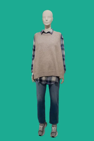 緑の背景に隔離されたニットベストと青いジーンズを身に着けている女性ディスプレイマネキンの完全な長さの画像 — ストック写真
