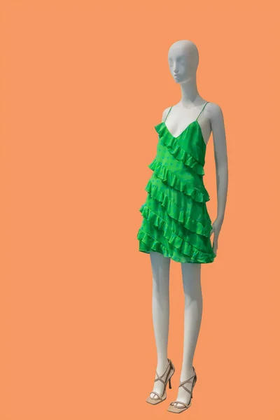 オレンジ色の背景に隔離されたファッショナブルな緑のドレスを身に着けている女性ディスプレイマネキンの完全な長さの画像 — ストック写真