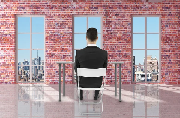 Empresário sentado na sala de tijolos — Fotografia de Stock
