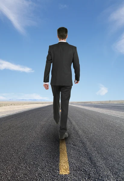 Businessman walking on road — Stock Photo, Image