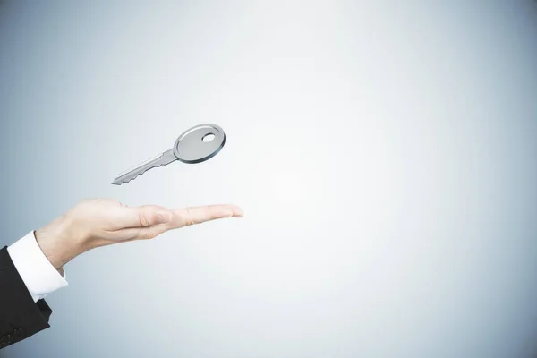 Großaufnahme Von Geschäftsmann Hand Hält Silbernen Schlüssel Auf Grauem Hintergrund — Stockfoto