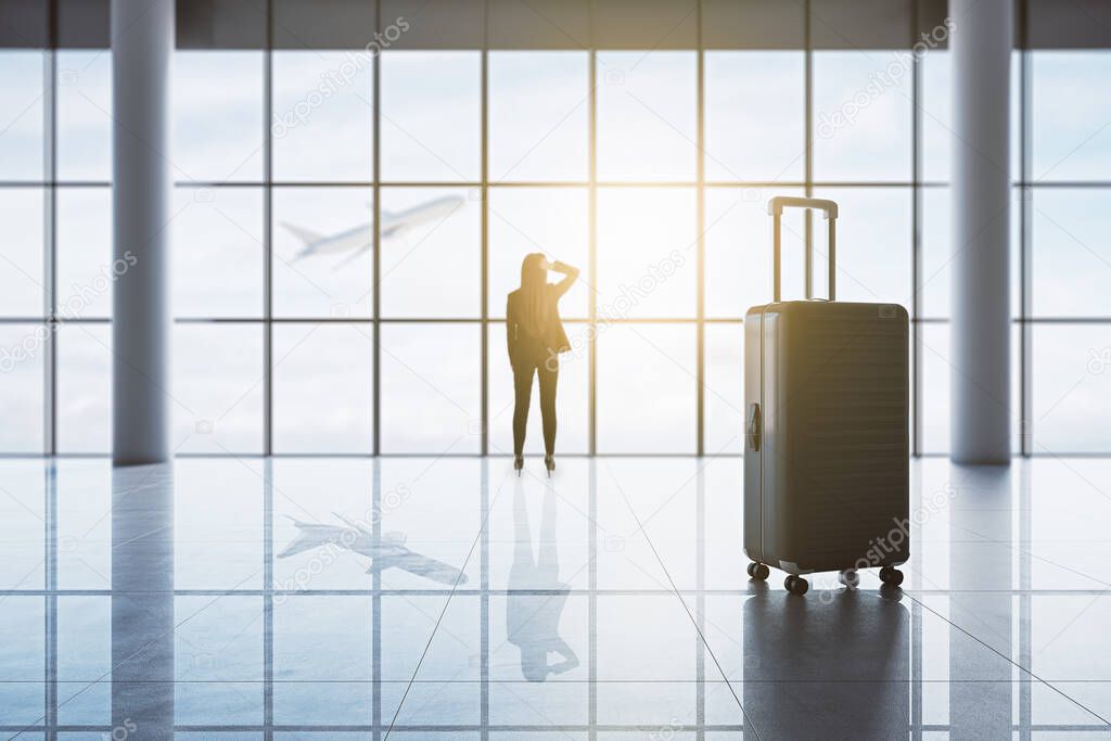 Back view of businesswoman and suitcases in luxury airport interior with panoramic city view and sunlight. Travel concept