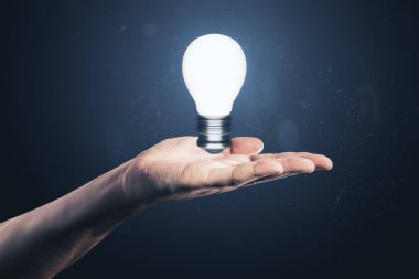 Close up of male hand holding glowing light bulb. Idea and innovation concept clipart