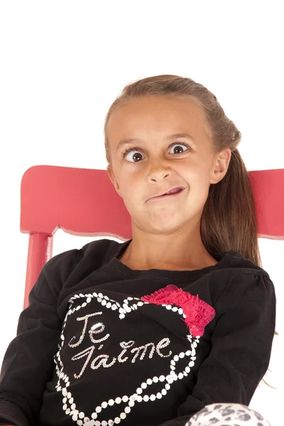 Chica en silla tirando de una cara divertida en camisa negra —  Fotos de Stock