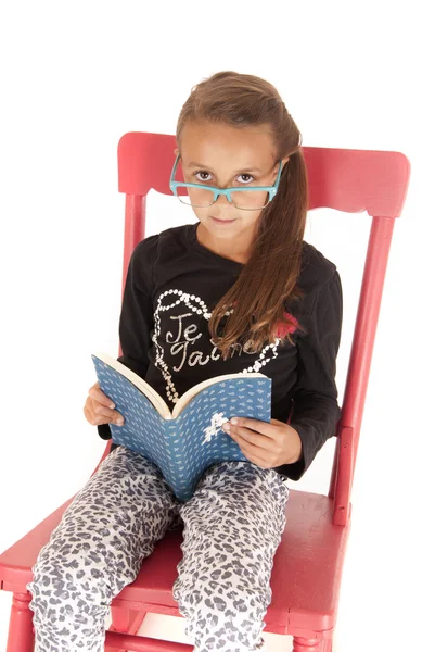 Mädchen schaut über Streberbrille und liest ein Buch — Stockfoto