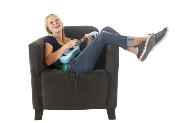 Rubia adolescente jugando un azul ukelele en un gris silla — Foto de Stock