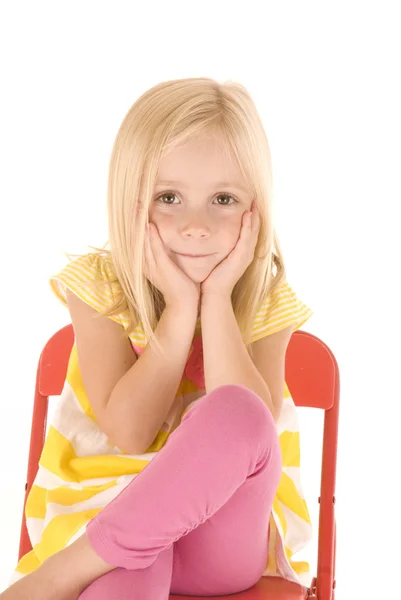 Young blonde girl in yellow striped shirt sitting in red chair c — Stock Photo, Image