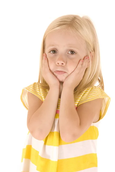 Young blonde girl in striped yellow top with hands on face sad Stock Image