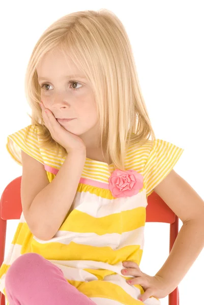 Young blonde girl sitting in a red chair resting her head in her — Stock Photo, Image