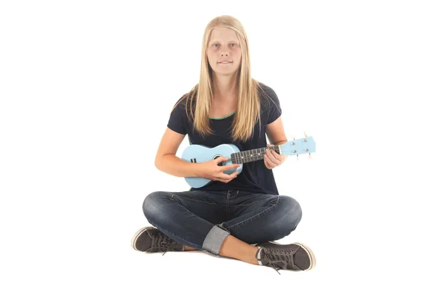 Девочка-подросток, сидящая на земле и играющая на голубом укулеле — стоковое фото