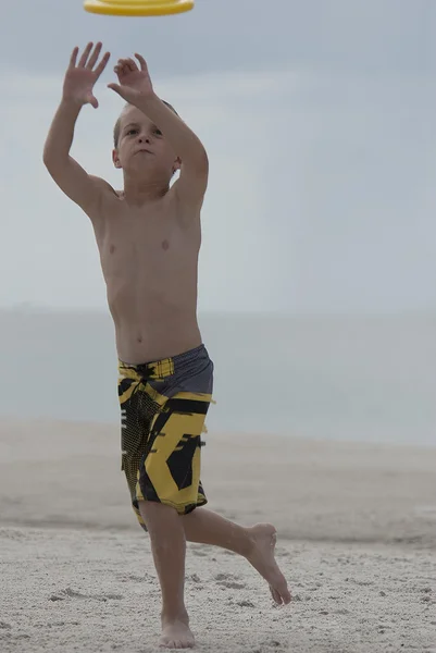 Giovane ragazzo che gioca cattura sulla spiaggia grande attenzione — Foto Stock