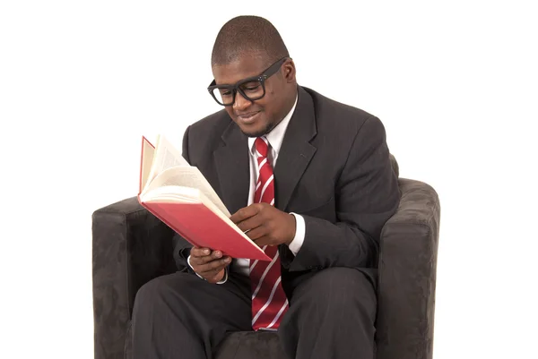 Young black man sitting in chair reading a book — Stock Photo, Image