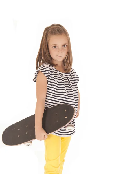 Young girl holding a skate board with a smirk on her face — Stock Photo, Image