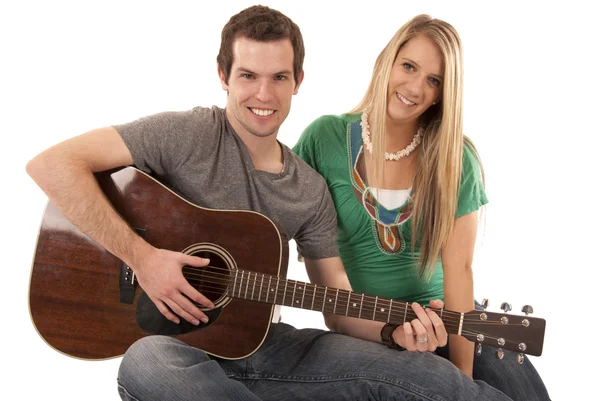 Jovem casal sentado tocando guitarra olhando para a câmera — Fotografia de Stock