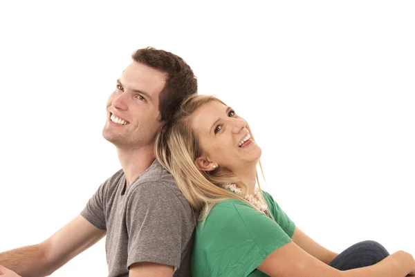 Young couple sitting back to back gazing up — Stock Photo, Image