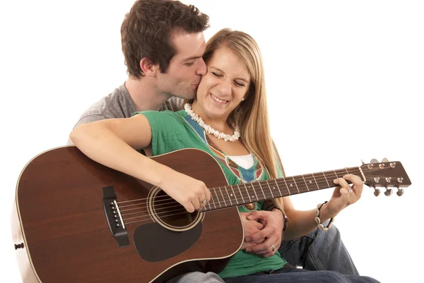 Young couple in love sitting playing guitar kissing — Stock Photo, Image