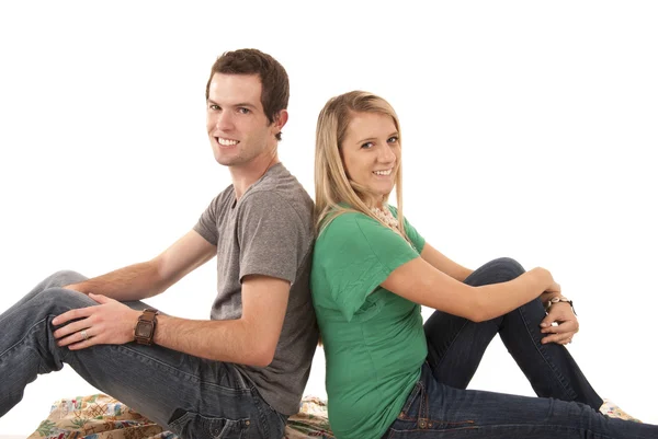 Young bouple sitting back to back on blanket looking at camera — Stock Photo, Image