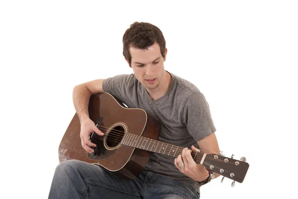 Young man playing acoustic guitar sitting — Stock Photo, Image